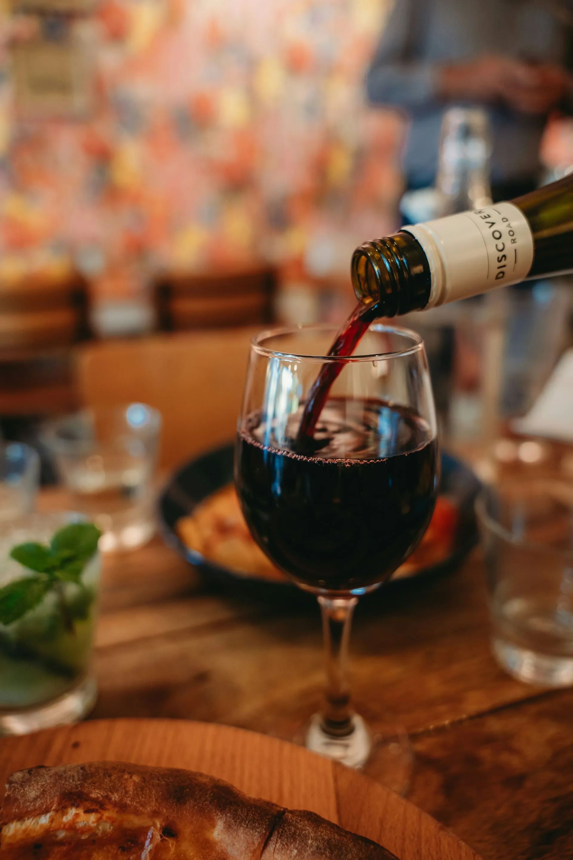 Red wine being poured into a glass at an intimate table setting